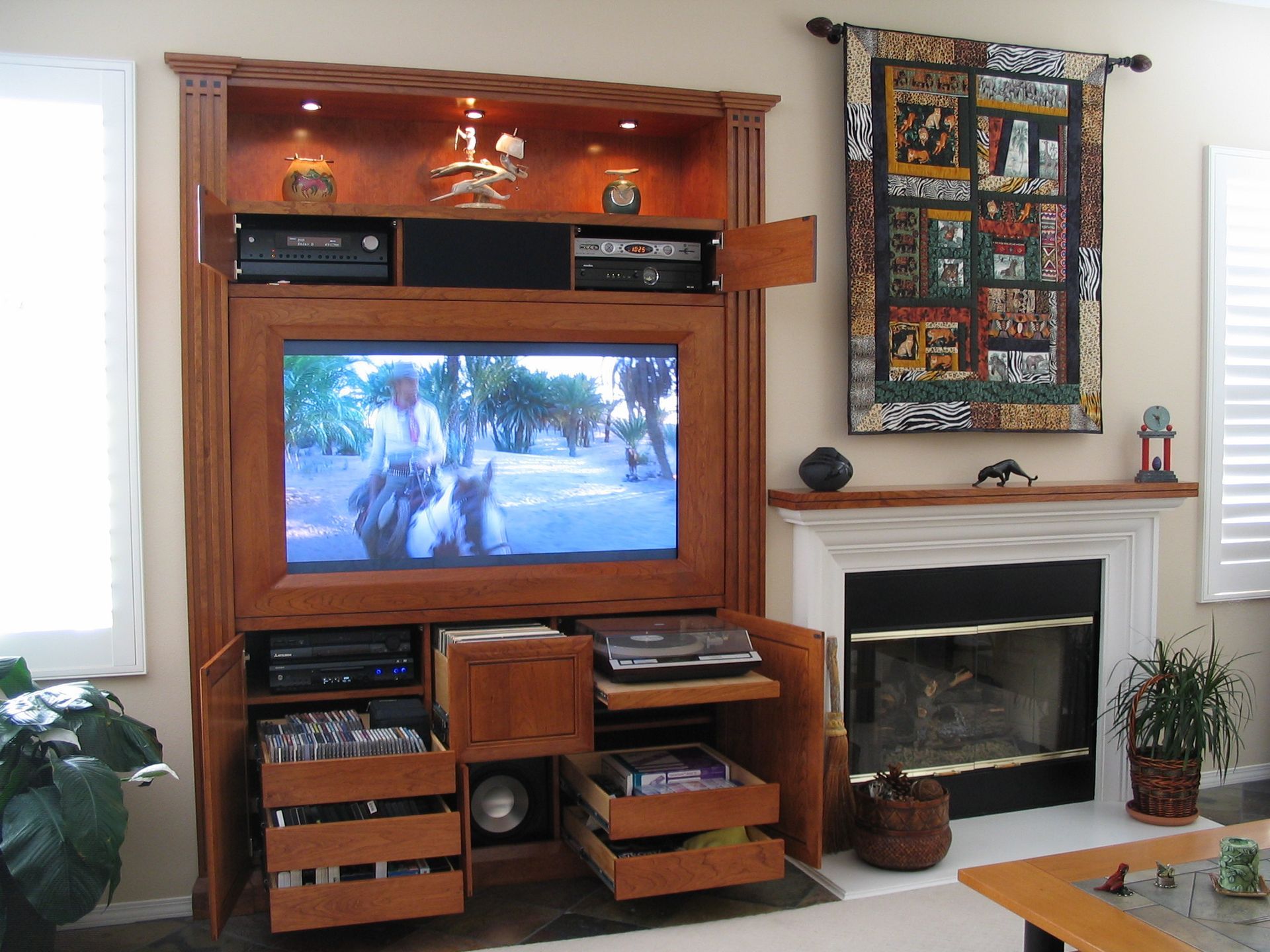 Wooden entertainment center with TV, fireplace, and decorative items.