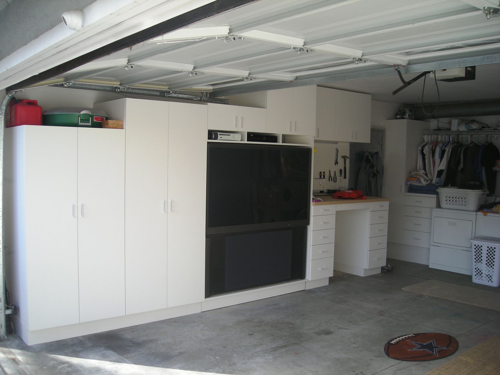Garage interior with white cabinets, a large black appliance, and concrete floor.