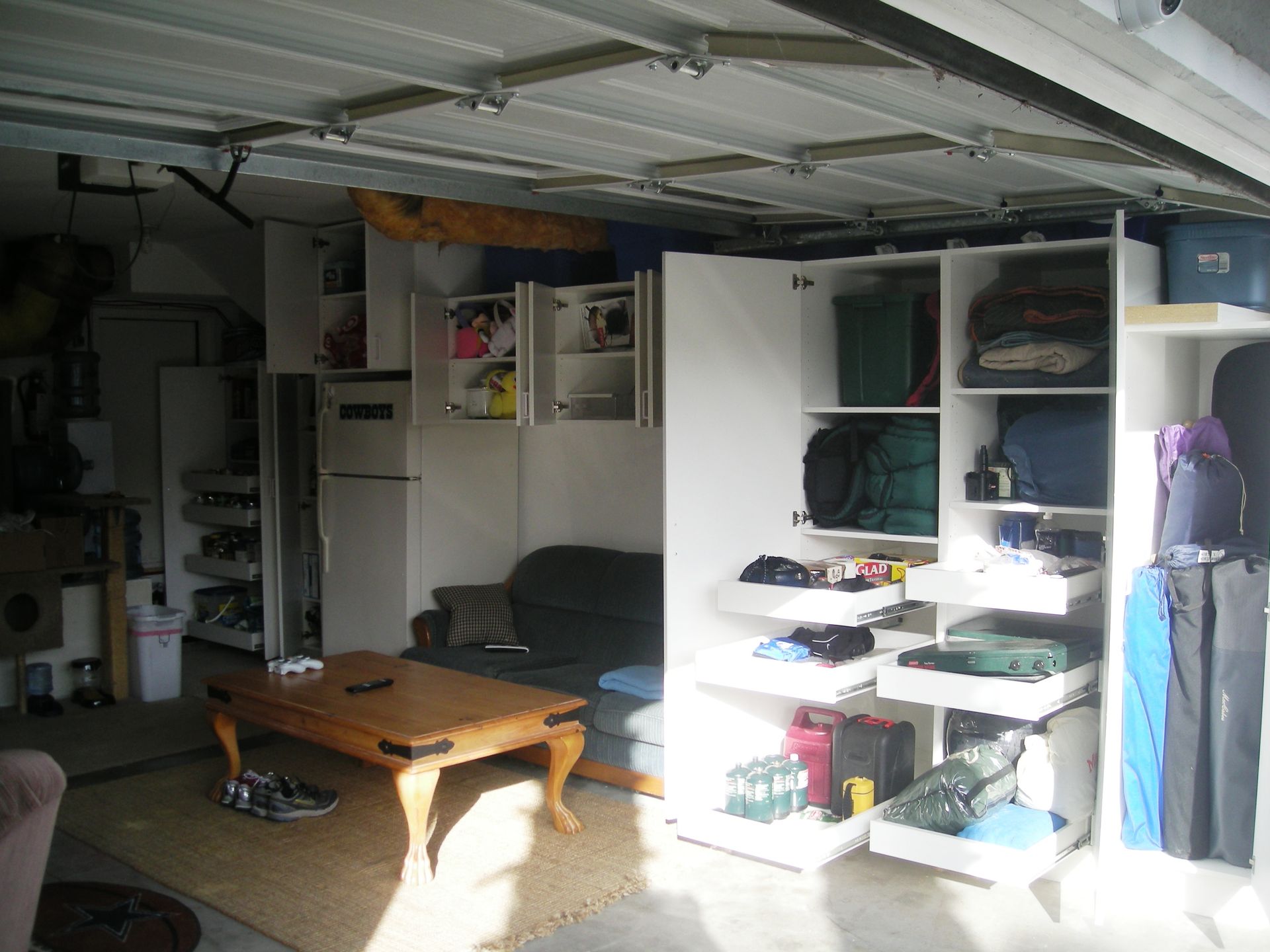 Garage converted to living space; couch, coffee table, storage cabinets, and various items stored.