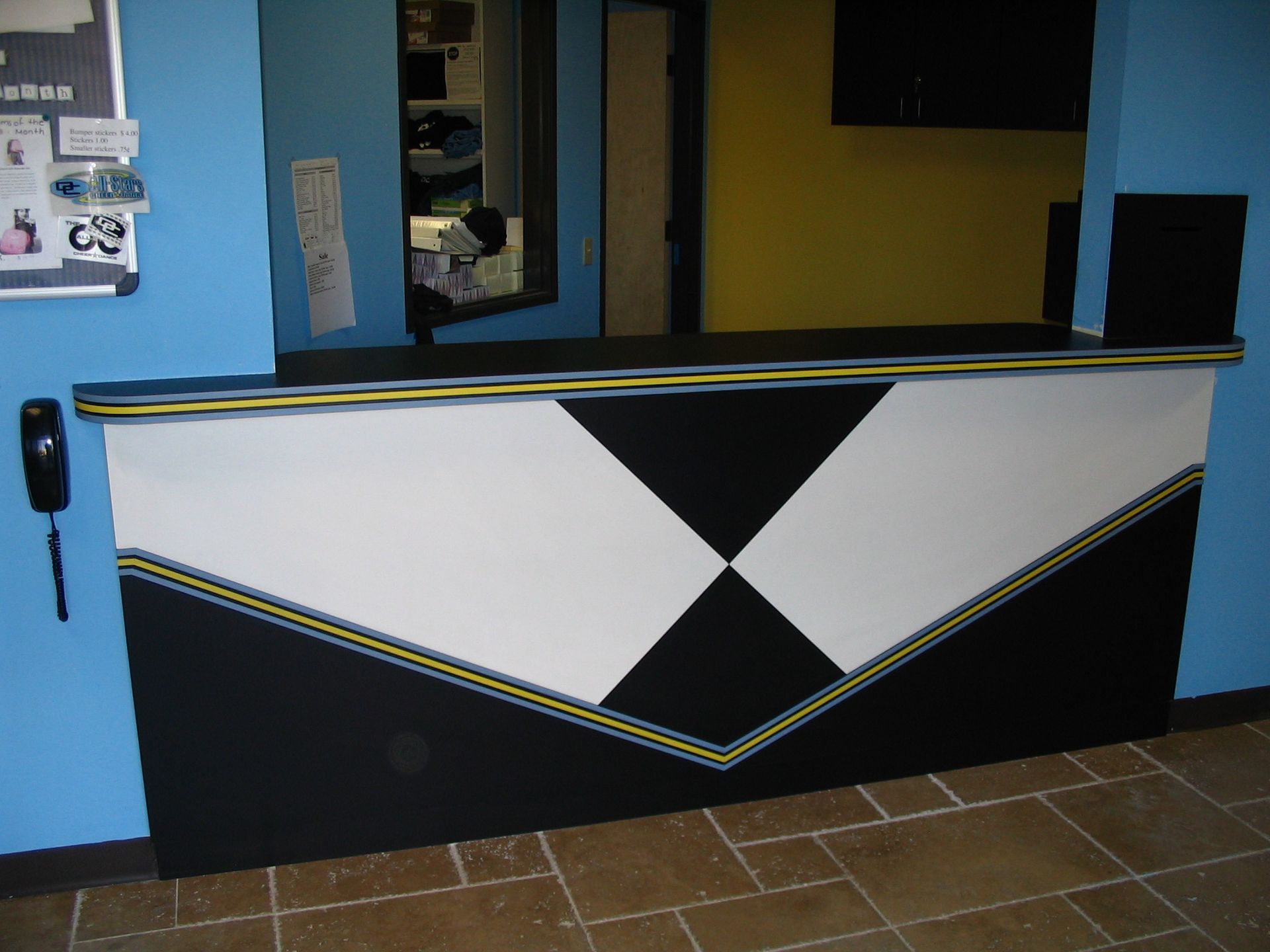 Reception desk with black, white, and yellow geometric design. Blue wall background.