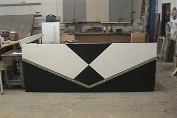 A black and white rectangular desk with a gold trim sits in a workshop setting.