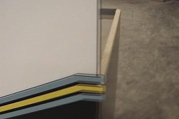 Close-up of a white panel with blue, yellow, and black stripes. Wooden frame on the right.