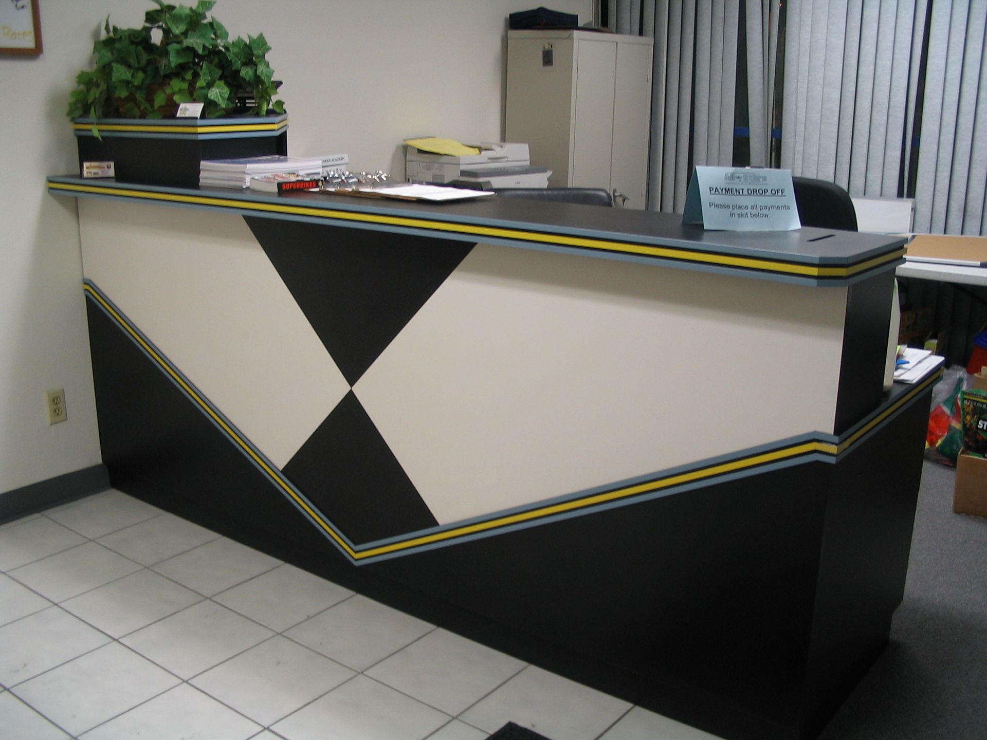 Reception desk with black and white geometric design and green plant.
