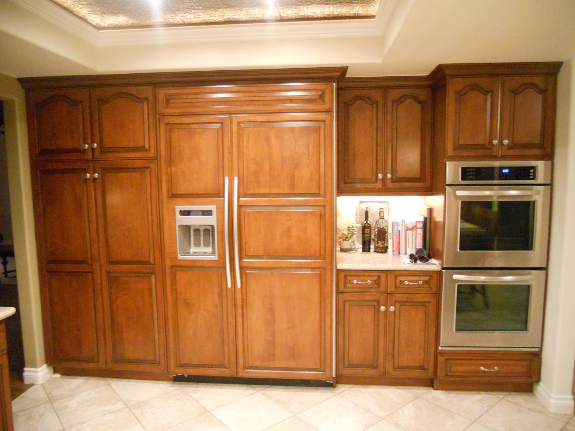 Kitchen with wooden cabinets, refrigerator, and stainless steel ovens.
