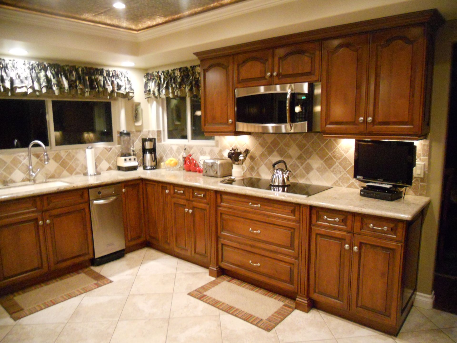 Kitchen with brown cabinets, stainless steel appliances, tile backsplash, and light-colored countertops.