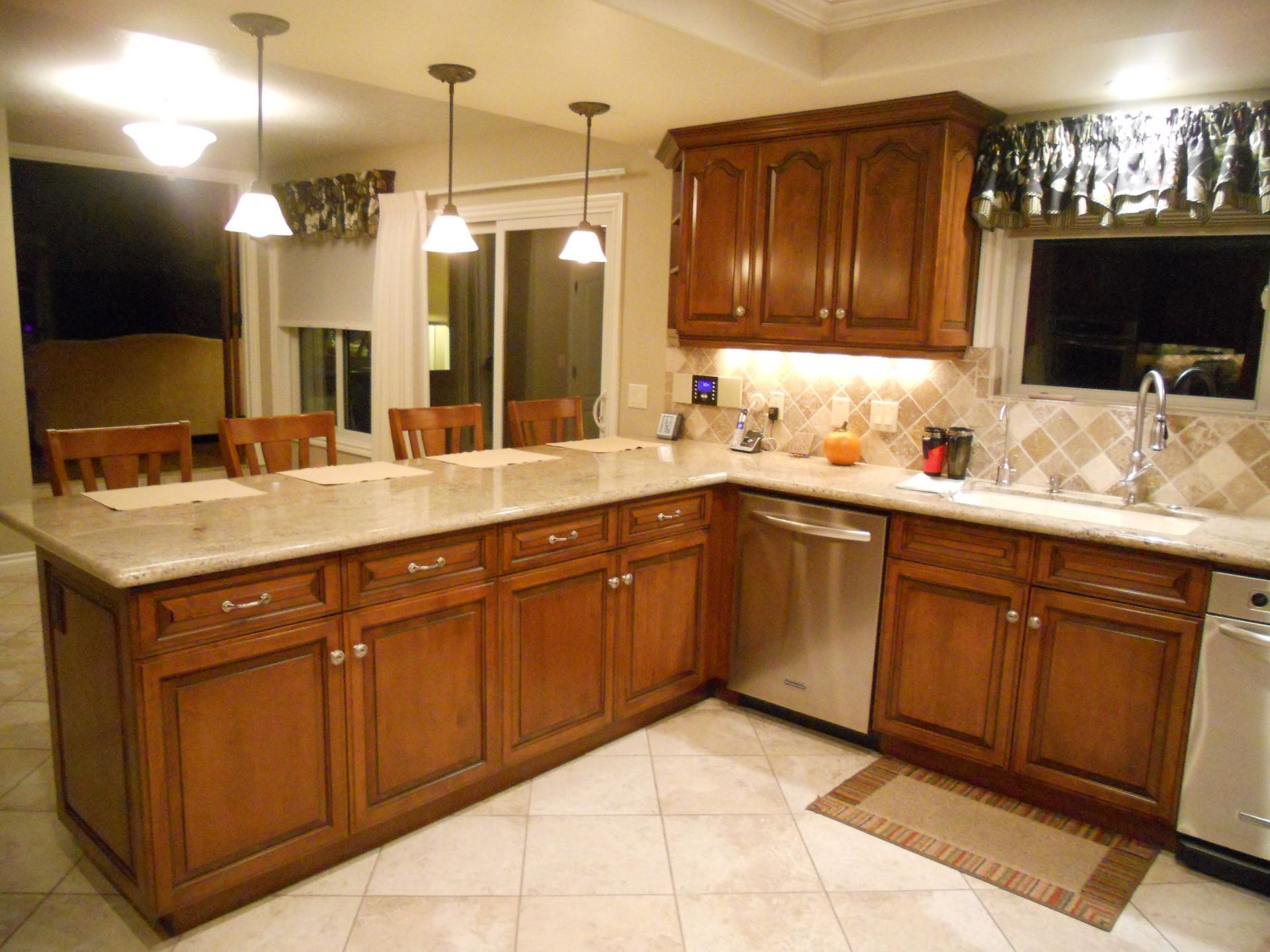 Kitchen with brown cabinets, stainless steel appliances, and beige countertops, with pendant lights.