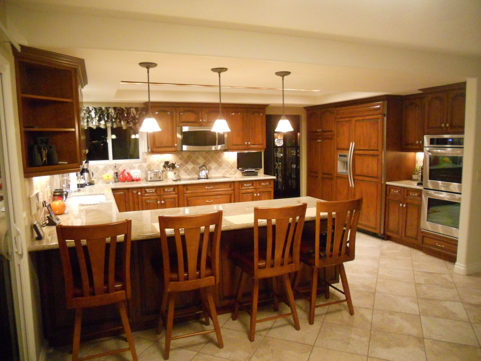 Kitchen with wooden cabinets, island with seating, and pendant lights.