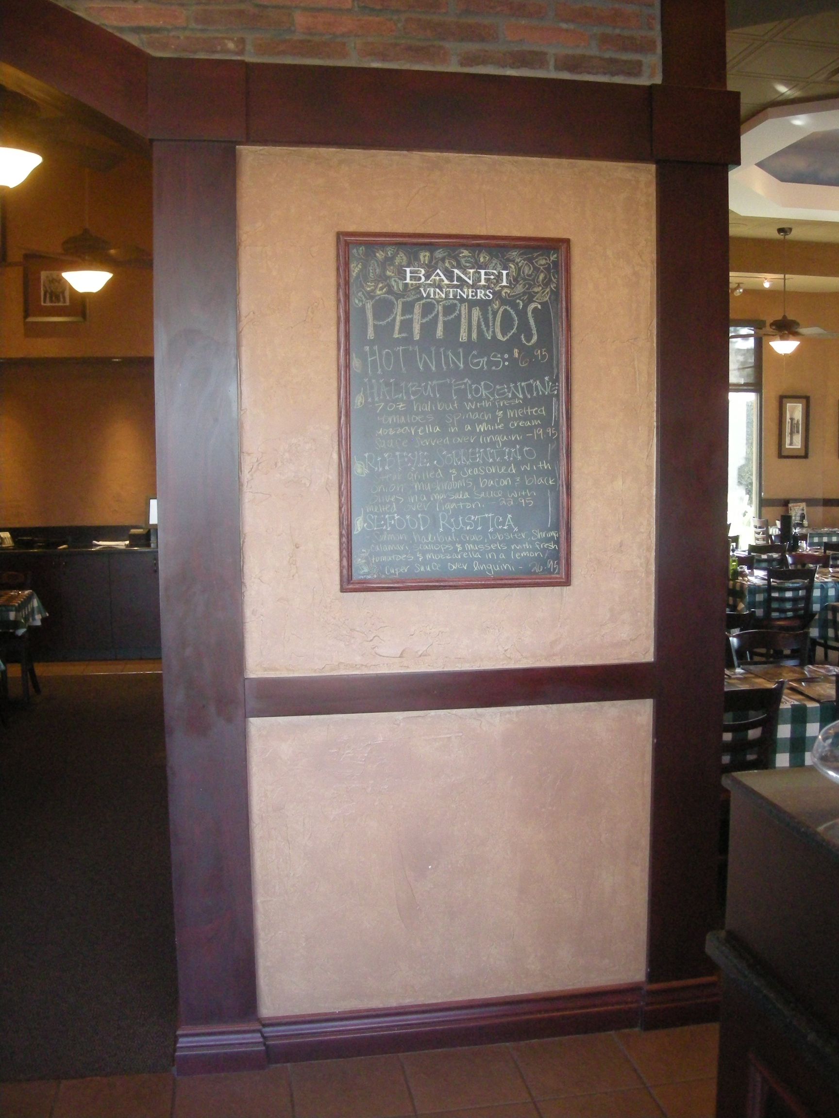 Wall with a chalkboard menu in a restaurant. Dark brown trim, beige stucco walls.