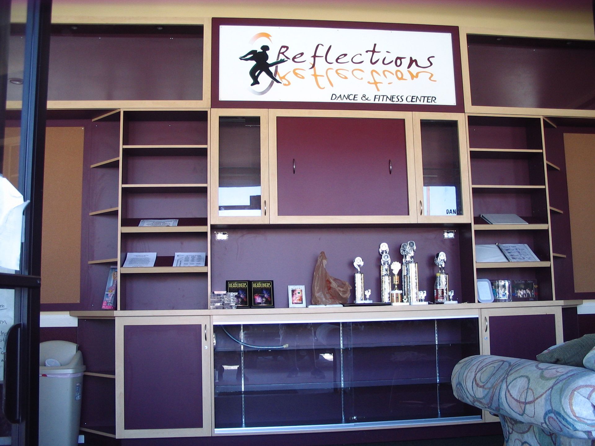 Purple shelves and cabinets with awards and books, under a business sign that says 