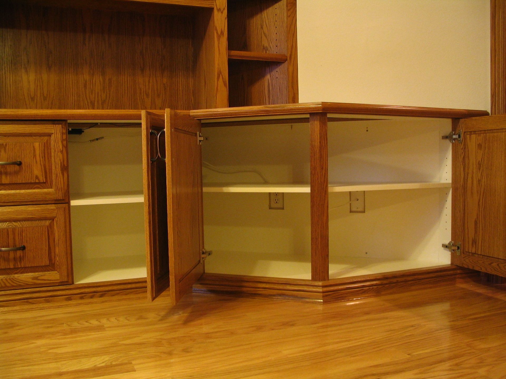 Wooden cabinets with open doors, revealing shelves inside. Oak wood with a natural finish.