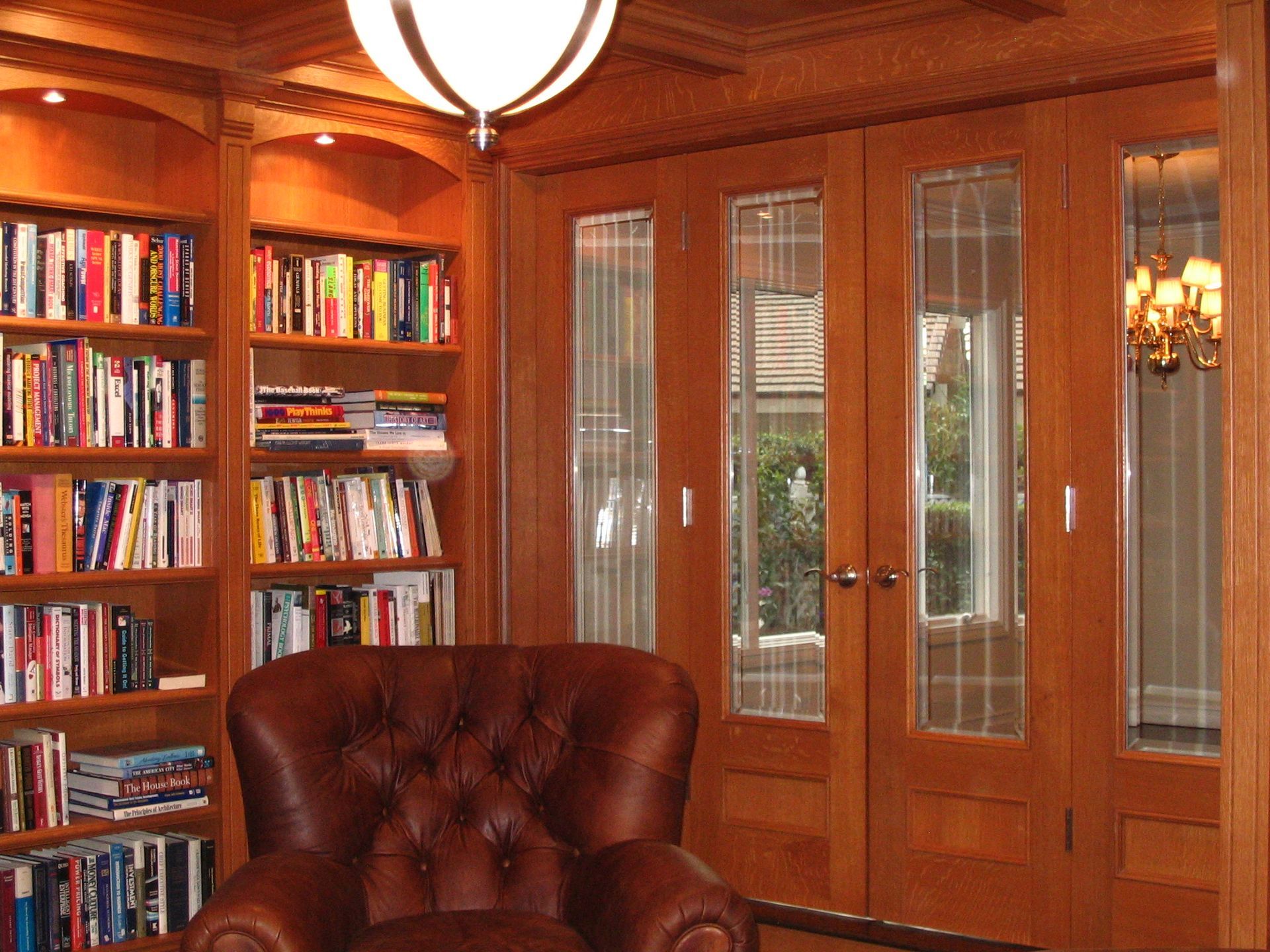 Cozy library with leather armchair, built-in bookshelves, and glass-paned doors.