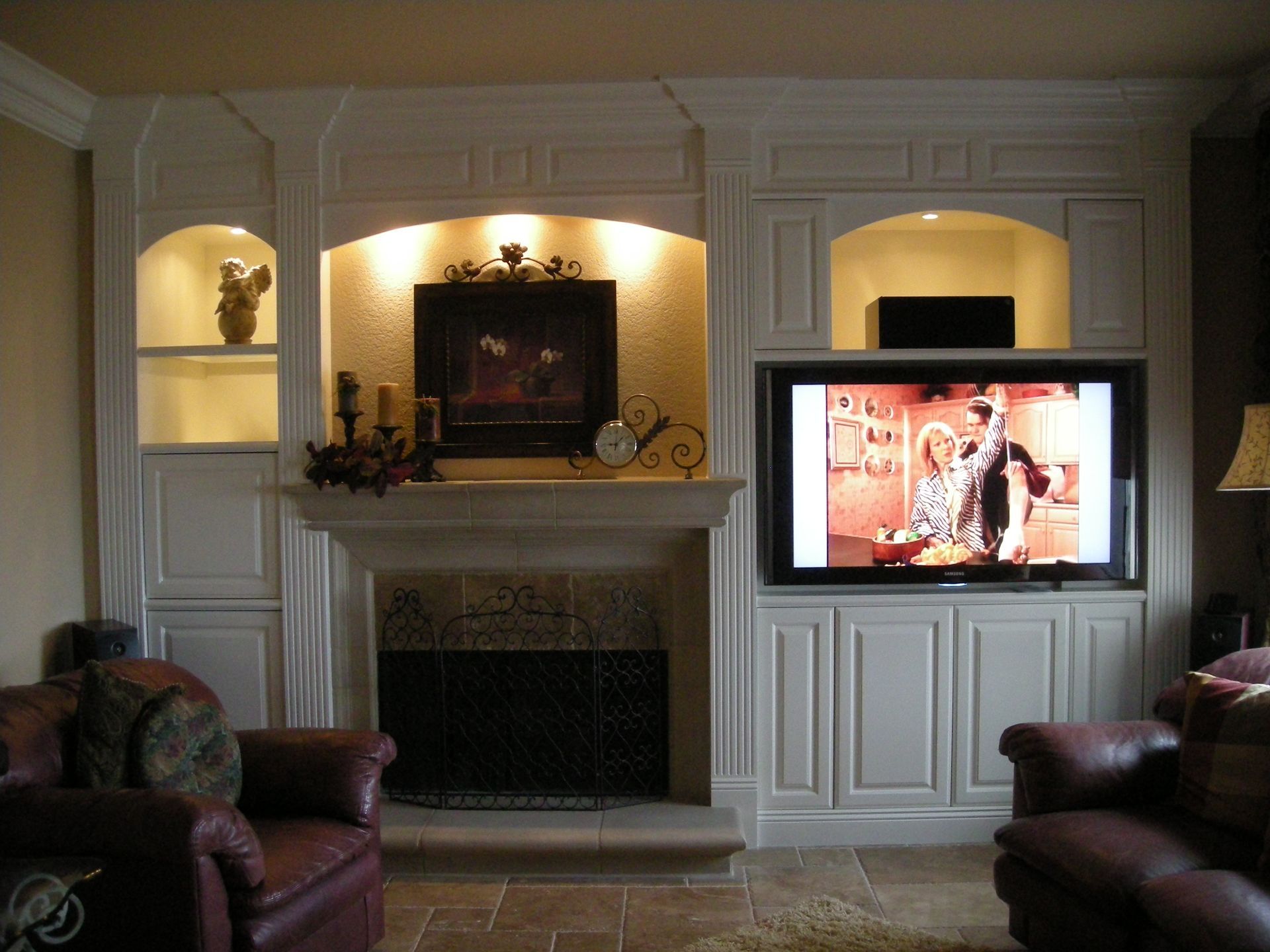 Living room with fireplace, built-in shelves, TV mounted above a cabinet.