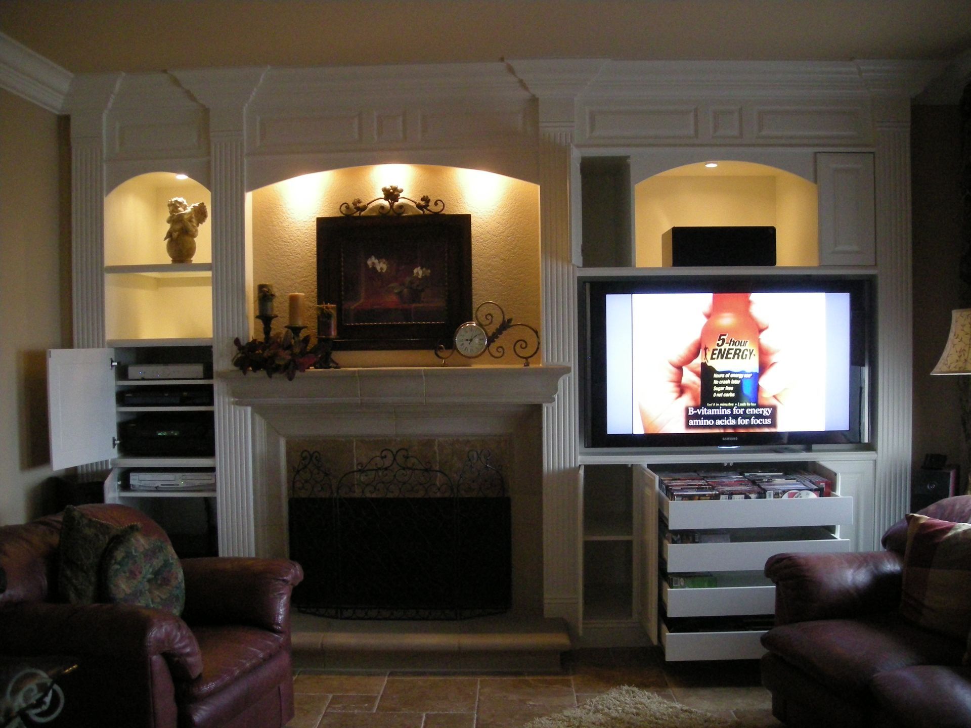 Living room with built-in entertainment center, fireplace, and two leather armchairs.