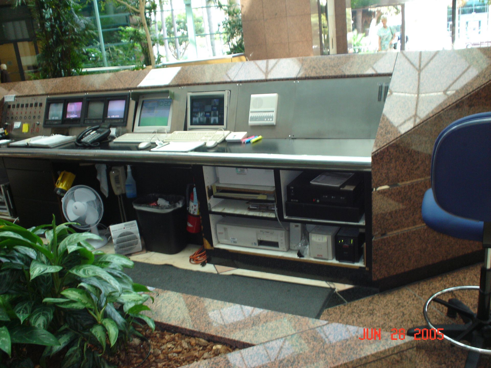 Reception desk with monitors, computers, and equipment in a building lobby.