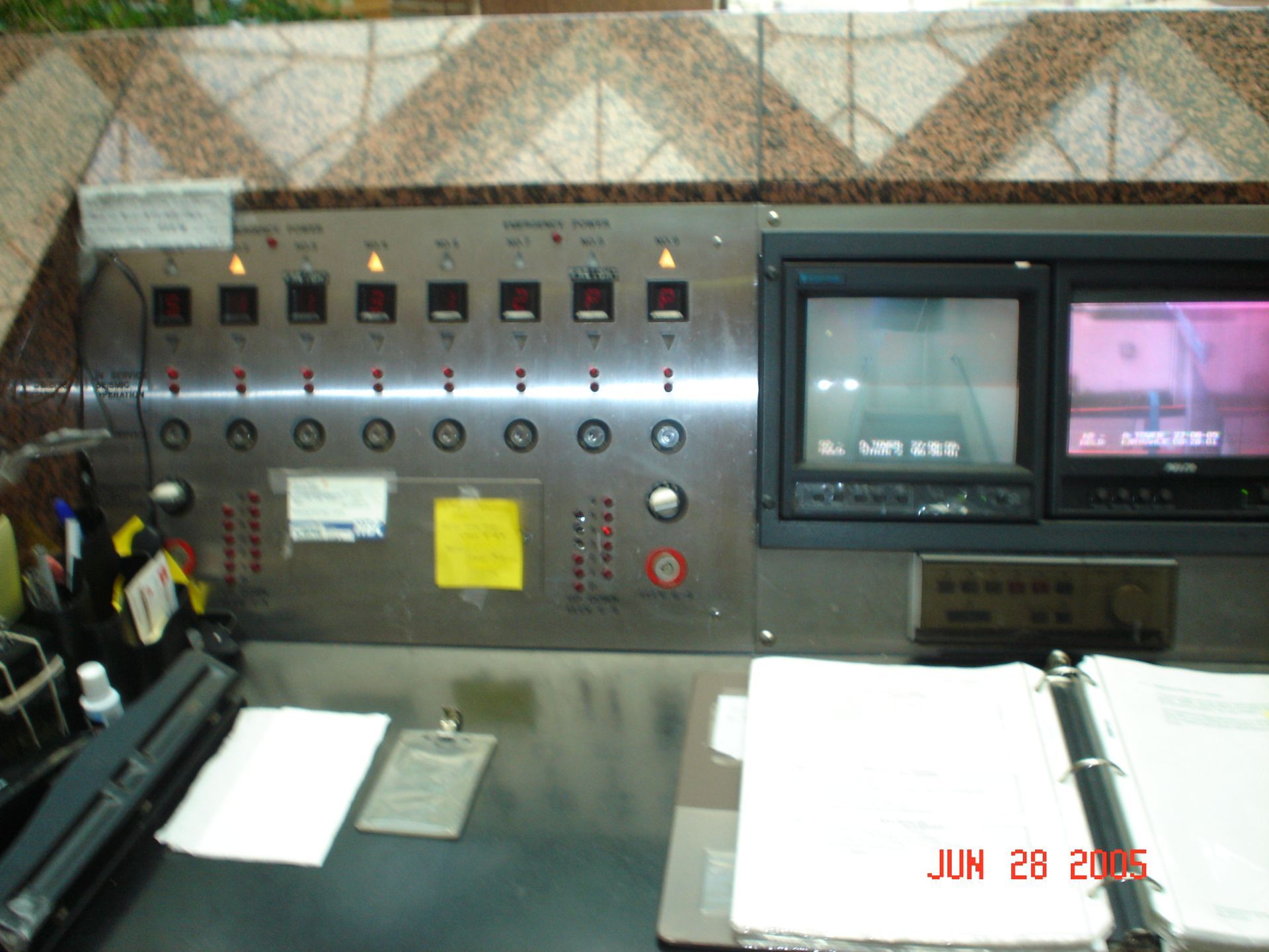 Control panel with monitors, switches, and gauges, likely in a facility.
