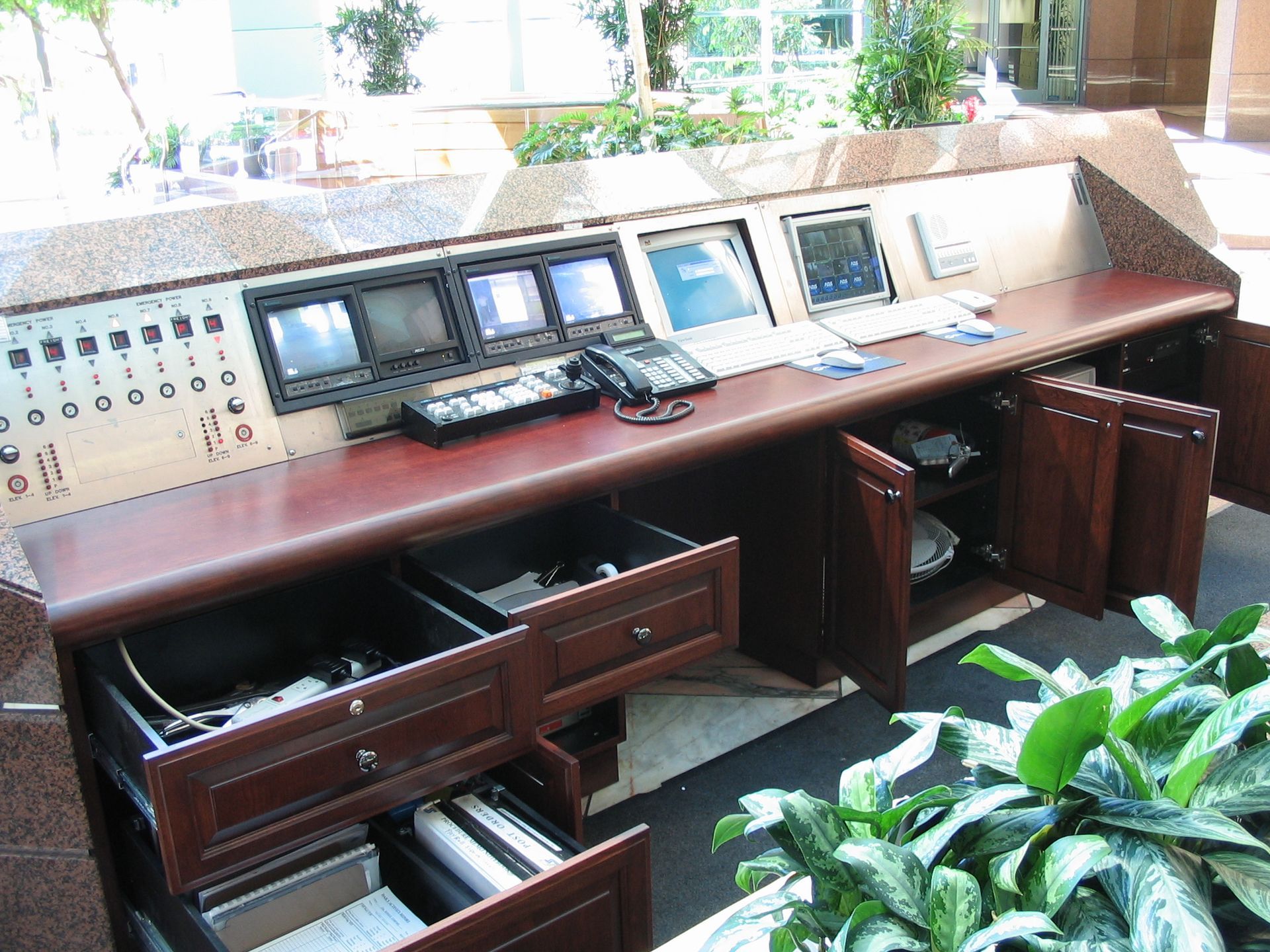 Control panel with monitors, drawers, and cabinet doors open; brown wood and stone.