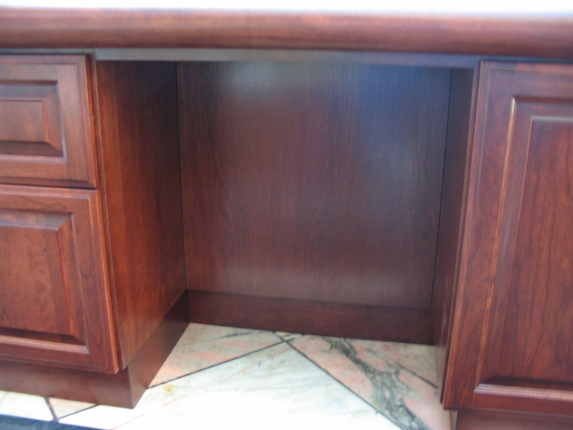 Wooden desk with an open central space and cabinet doors on either side.
