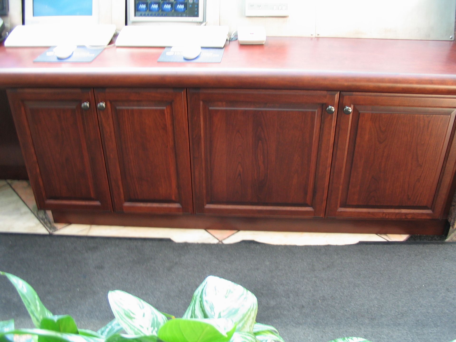 Wooden cabinets beneath a counter, with a red-brown surface. Dark wooden doors.