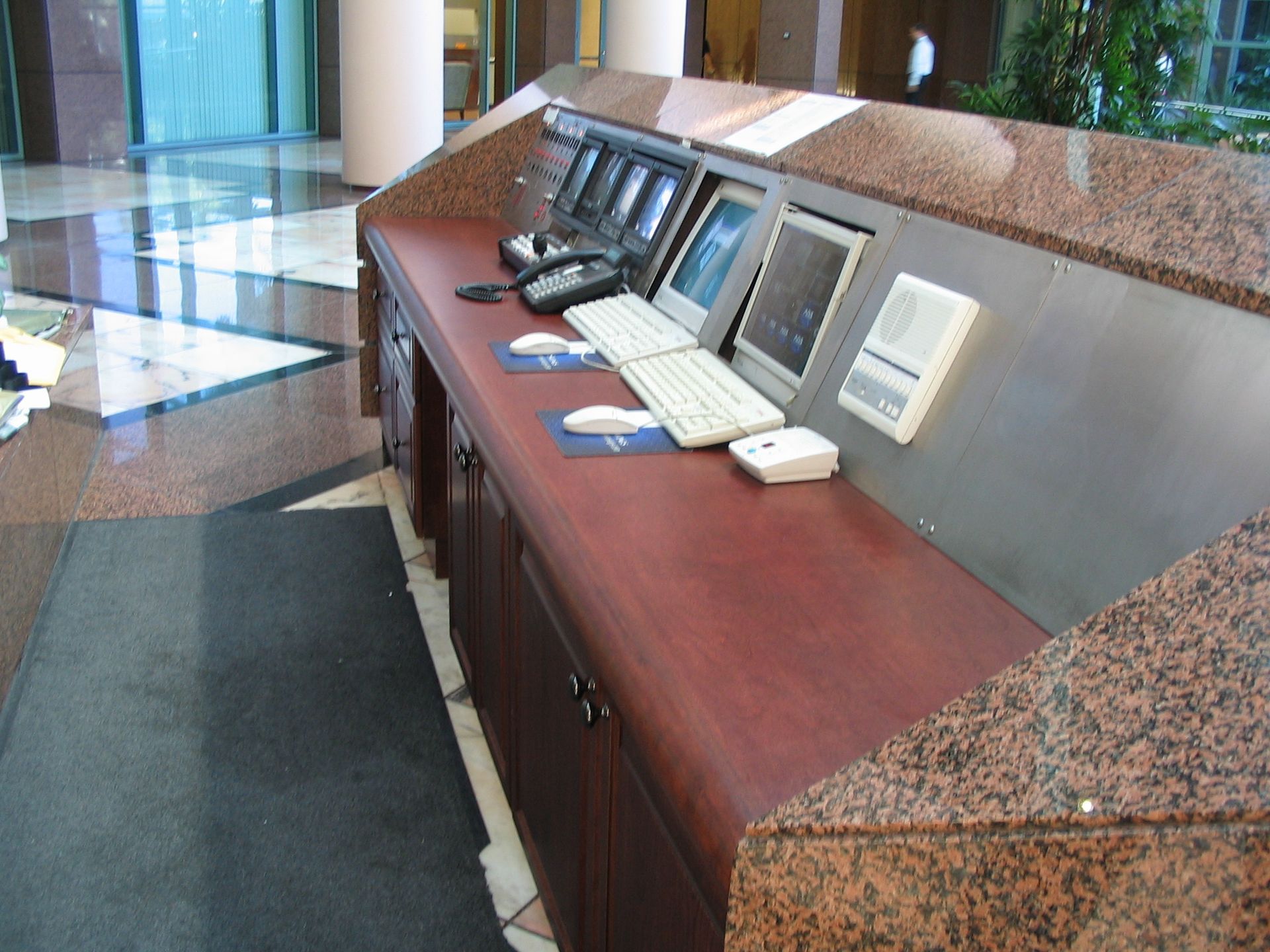 Reception desk with granite top, monitors, keyboard, mouse, and phone in an office building.