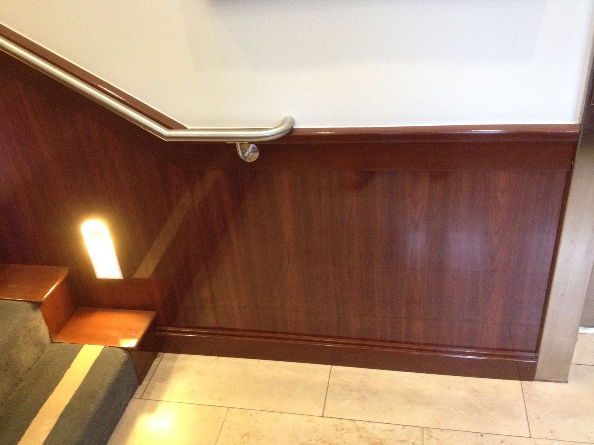 Wooden paneling with a metal handrail and illuminated steps.