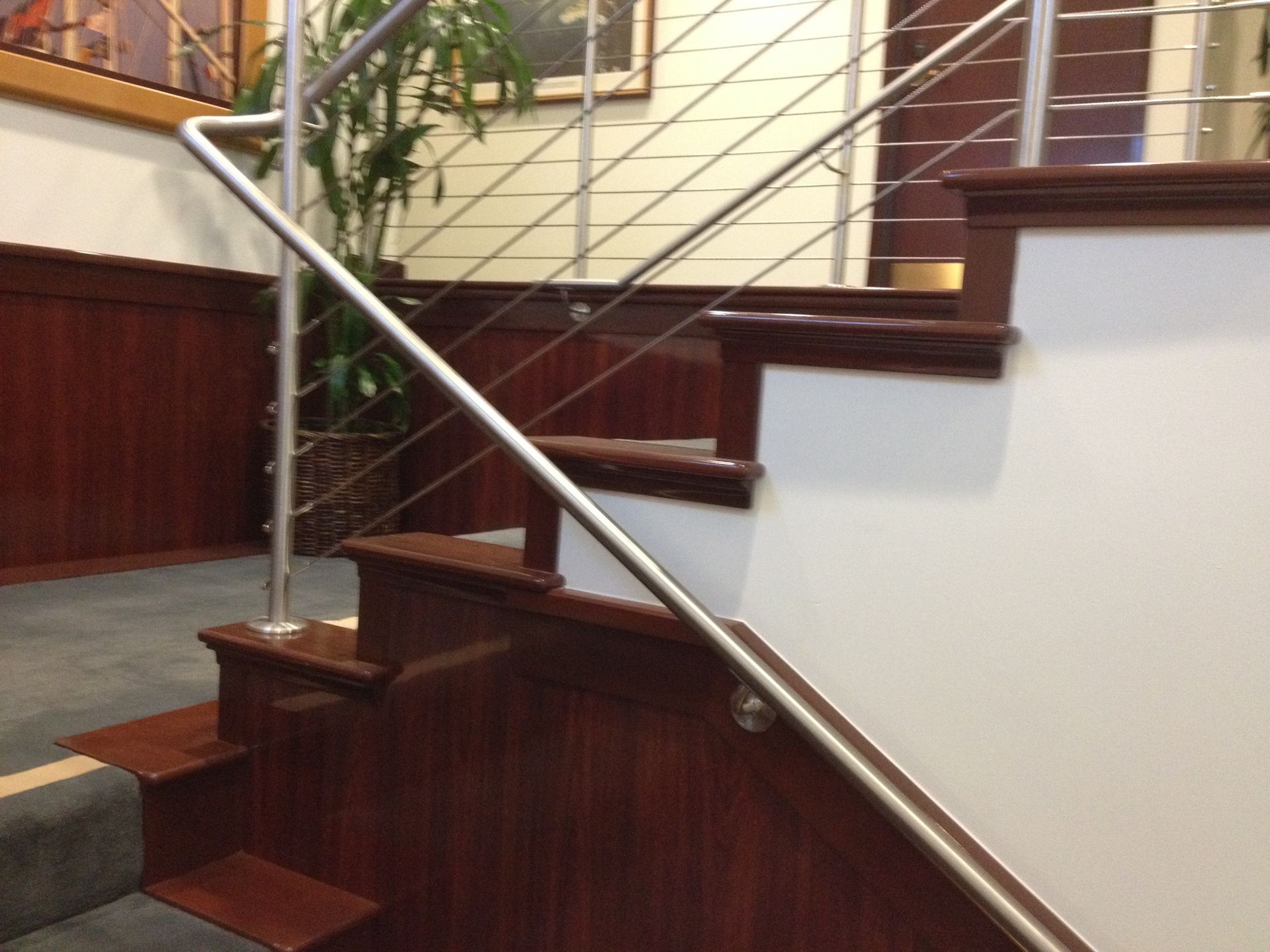 Staircase with wooden steps and railing, stainless steel cable and handrail.