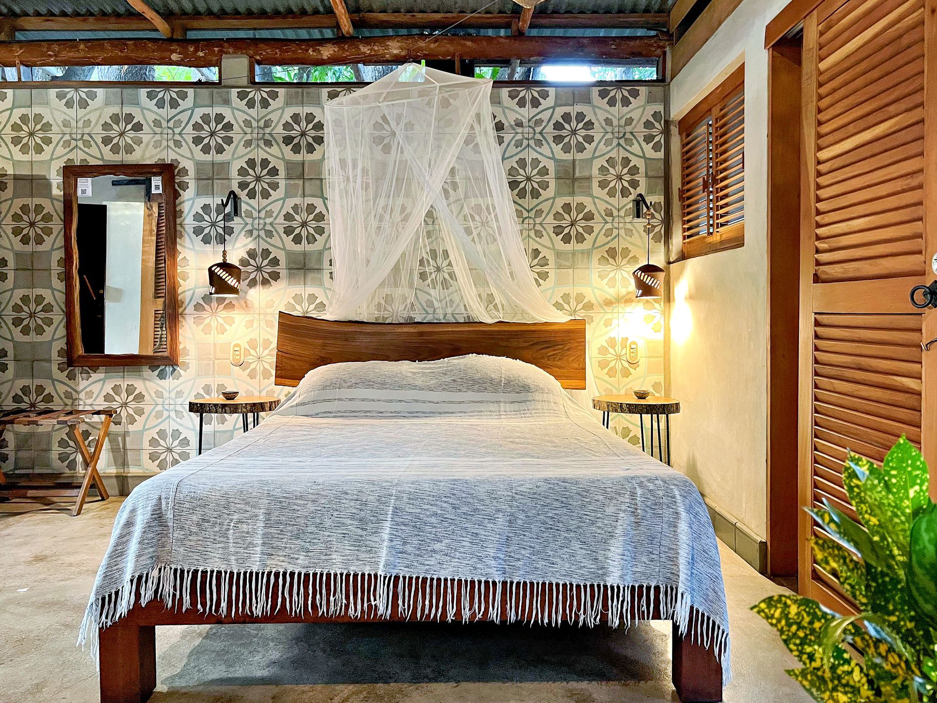 Bedroom with wooden bed, patterned tile wall, and sheer canopy.