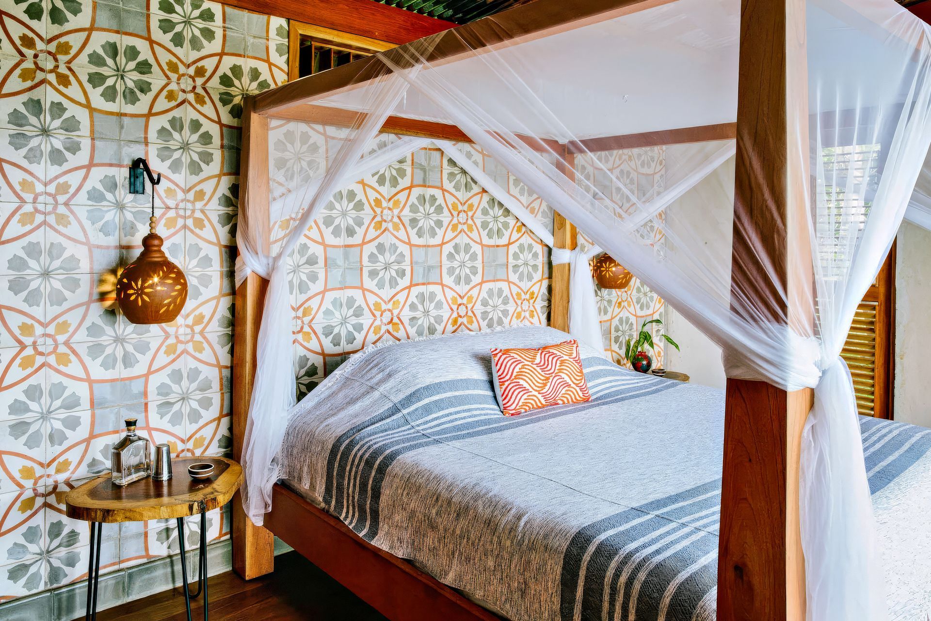 Bedroom with canopy bed, patterned tile wall, side table, and decorative lantern.