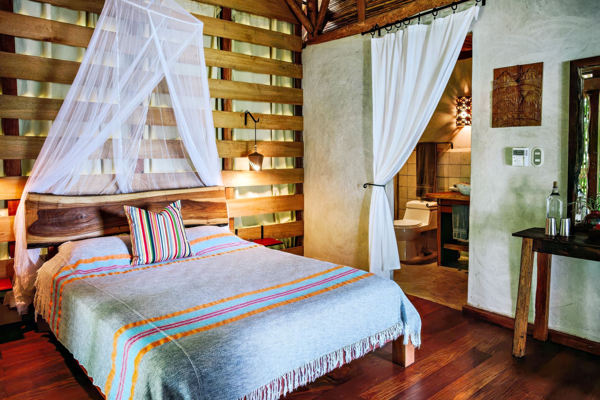 Bedroom with wooden walls, bed with canopy, and bathroom visible.