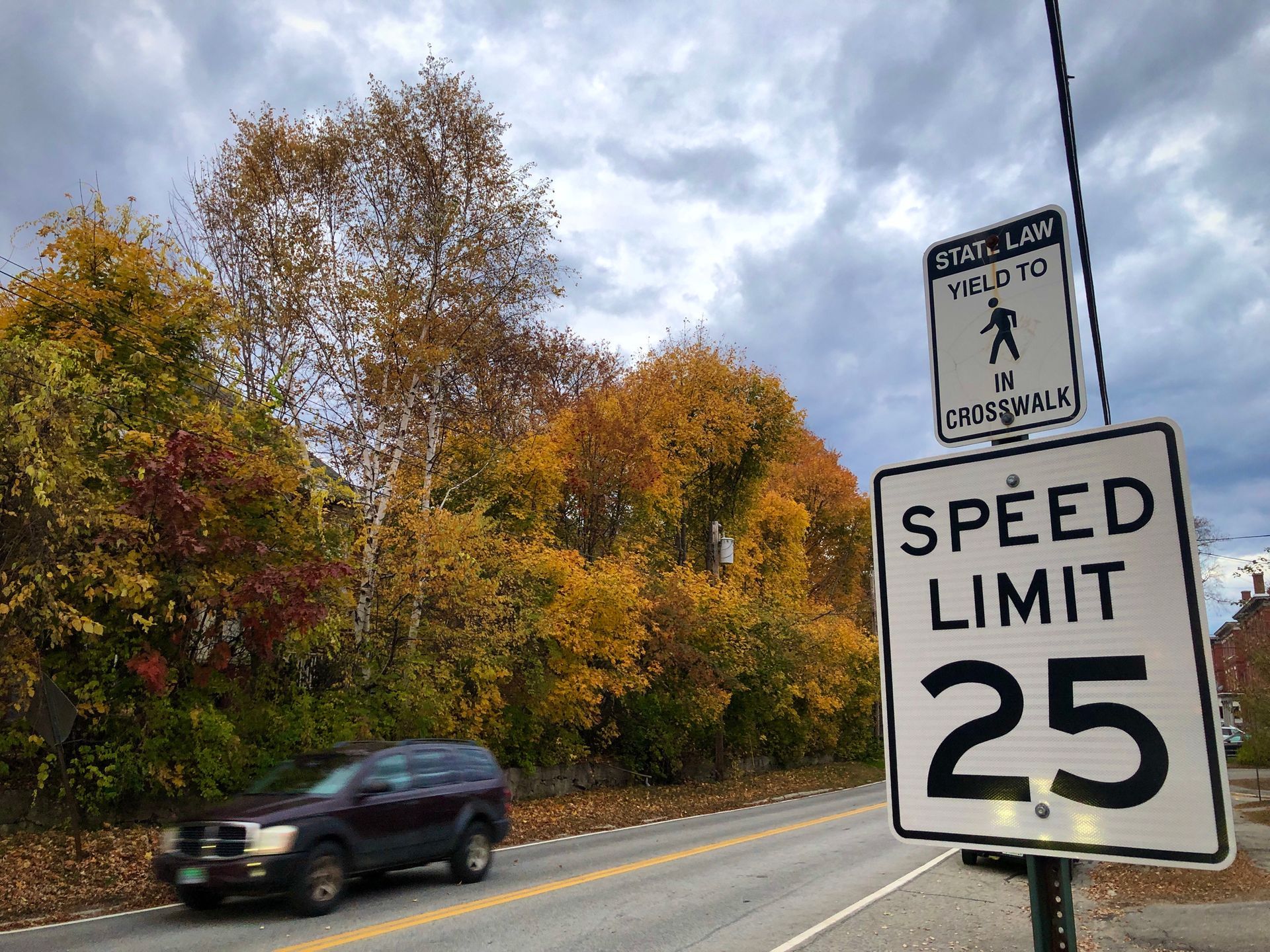 Car driving down a street with a 25 mph speed limit sign Car driving down a street with a 25 mph speed limit sign