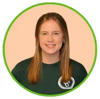 Woman with shoulder-length light brown hair smiles at the camera, wearing a dark green t-shirt with a logo.