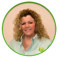 A woman with curly blonde hair wearing a light green shirt, smiling. She is in a green-bordered circle.