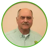 Mature man with a mustache in a light green button-down shirt, inside a green circle.