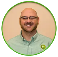 Bald man with glasses smiling in a light green collared shirt inside a green circle.