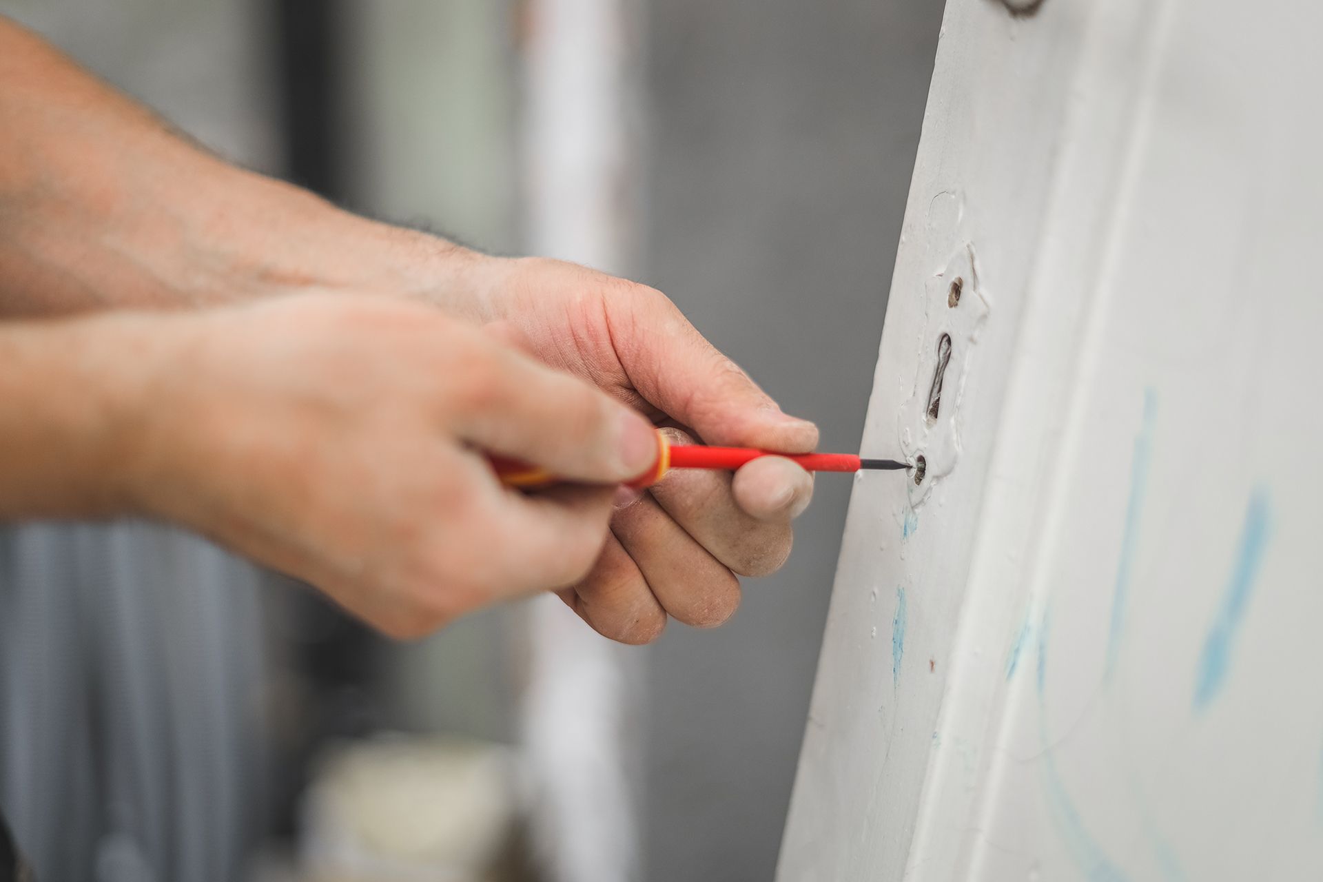 A person is using a screwdriver to screw a screw into a wall.