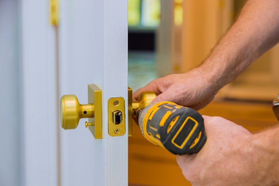 A man is fixing a door with a drill.