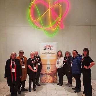 Group poses near a banner with a heart-shaped neon light backdrop.
