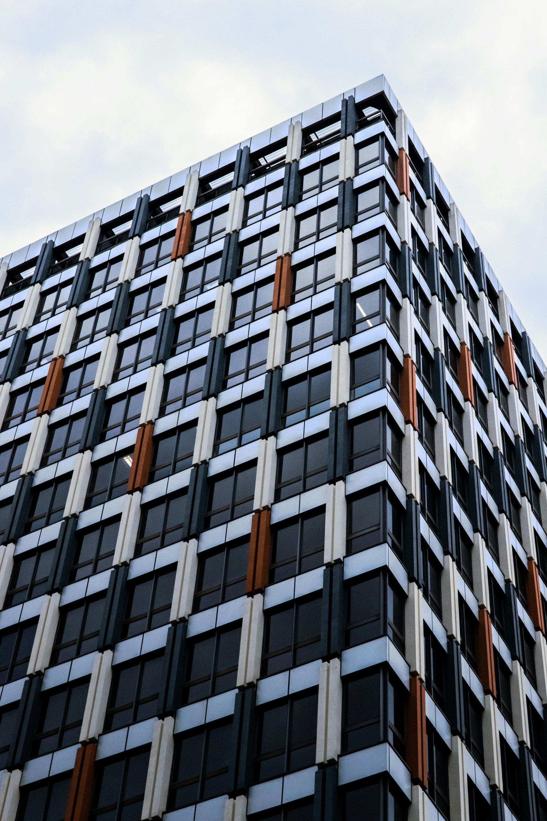 Modern multi-story building with a patterned facade, dark windows, and orange accents.