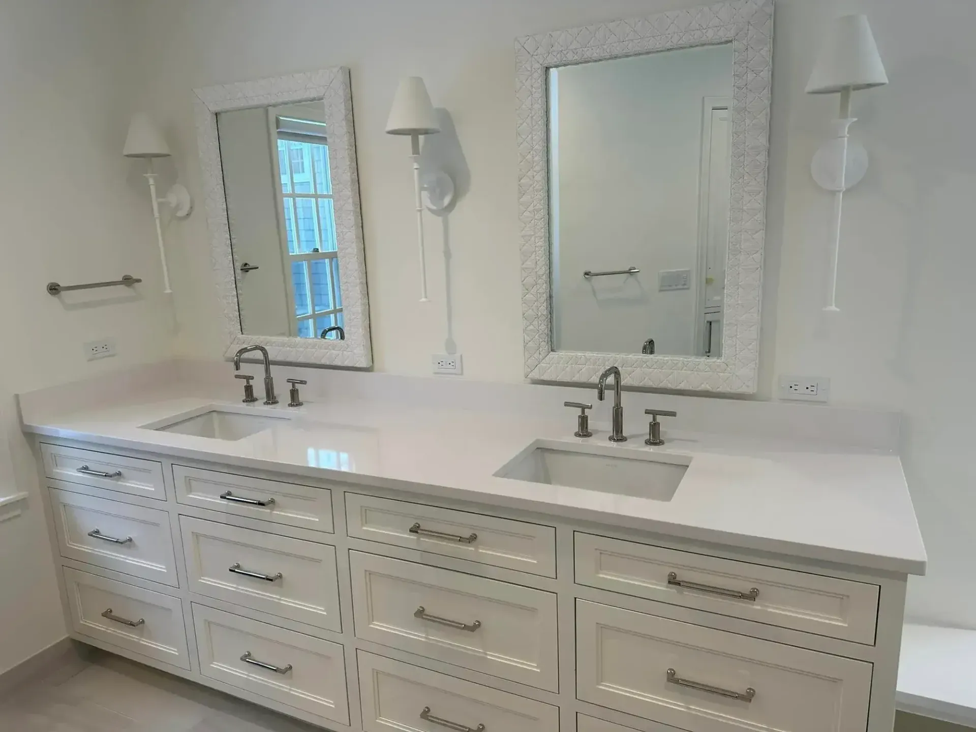 White double vanity with two sinks, mirrors, and sconces.