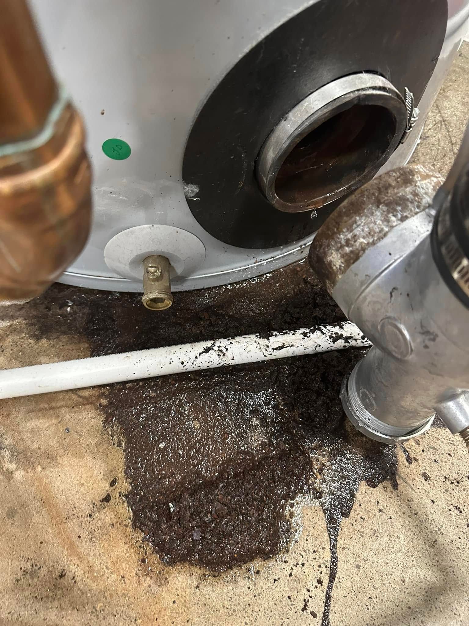 Water heater leaking onto the floor. Visible corrosion and pipes.