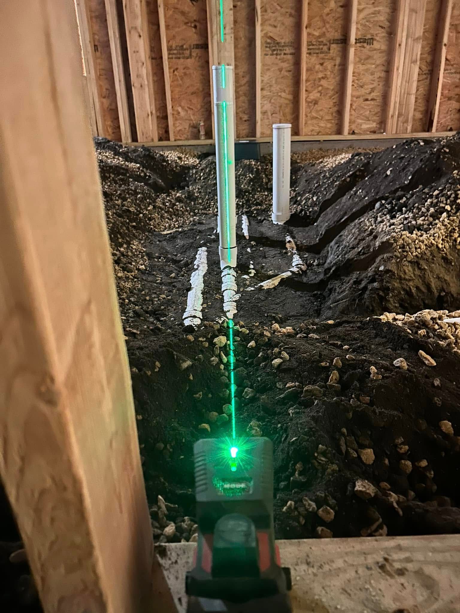 Green laser level projecting a line onto a wall in a construction setting.