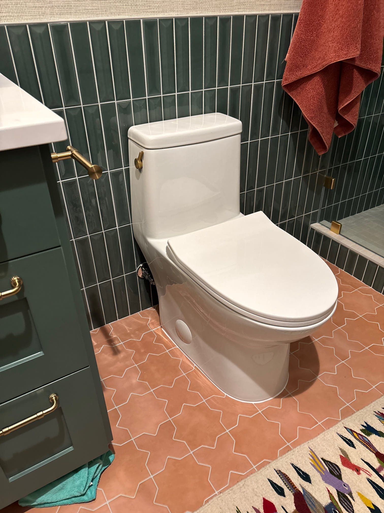Person sitting on a toilet in a public restroom with three other toilets.