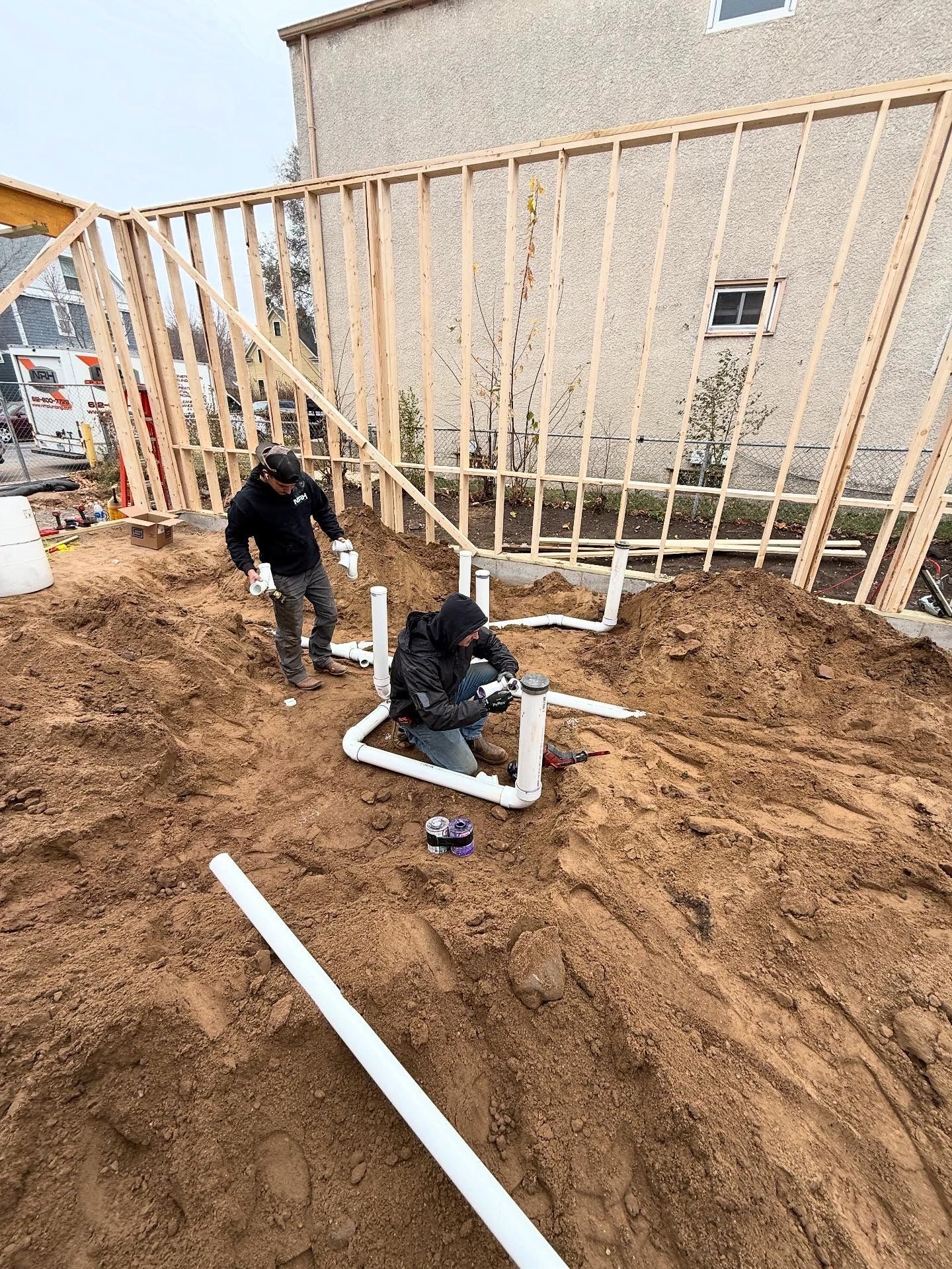 Electrician works on wiring in a ceiling, next to wooden studs.