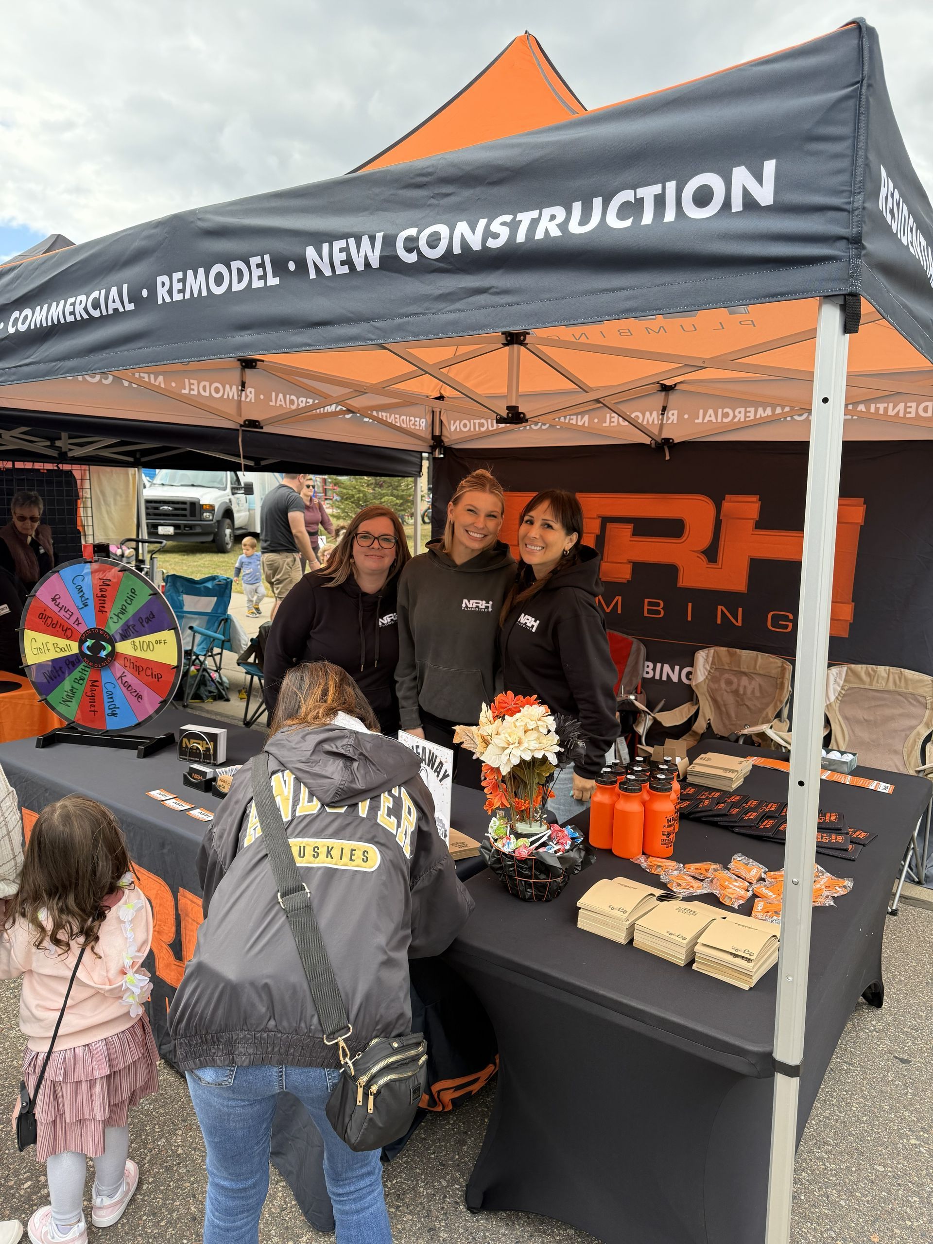 Booth with three women, products, and a prize wheel; 