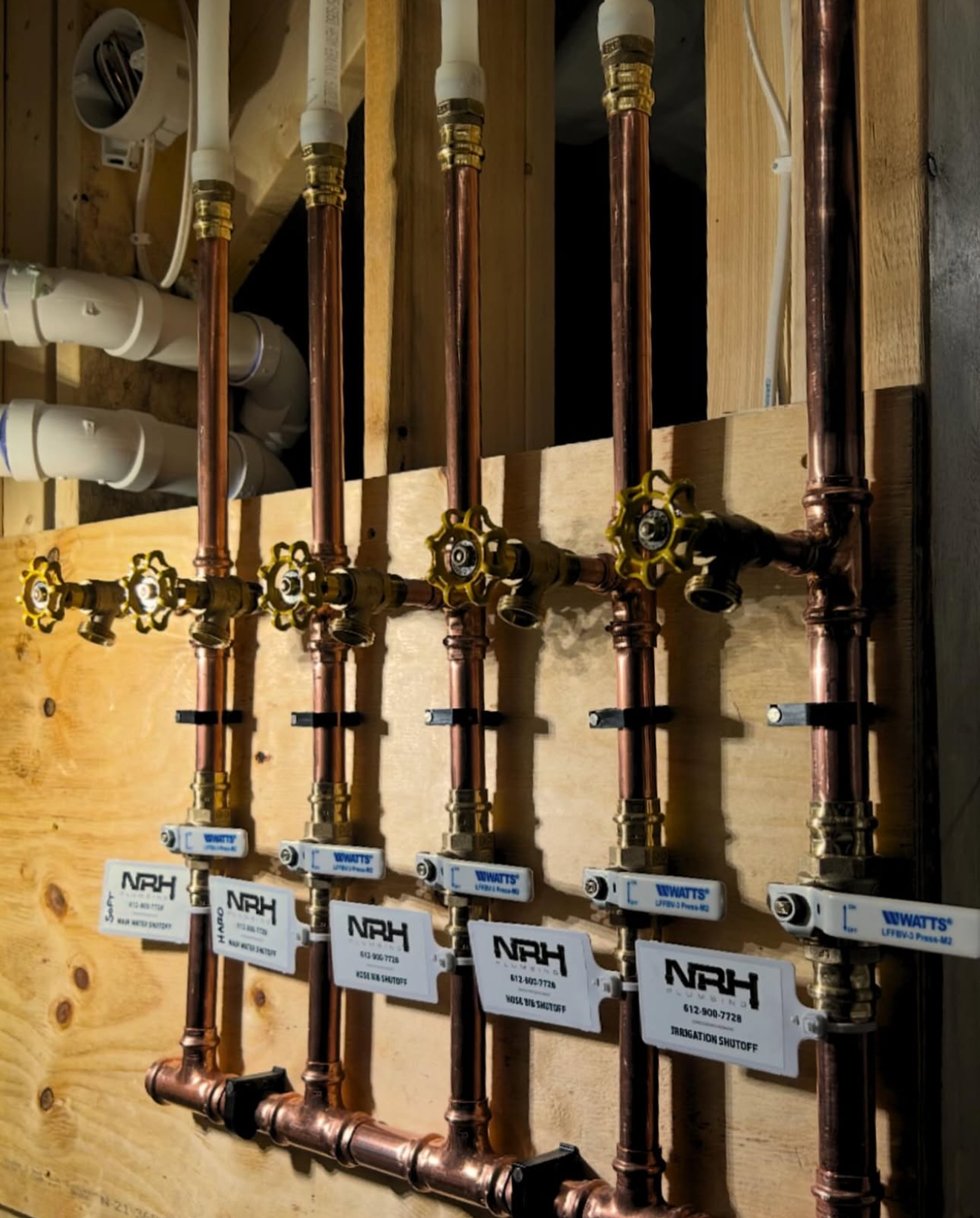 White PVC pipes in a trench, connected to a brick building.