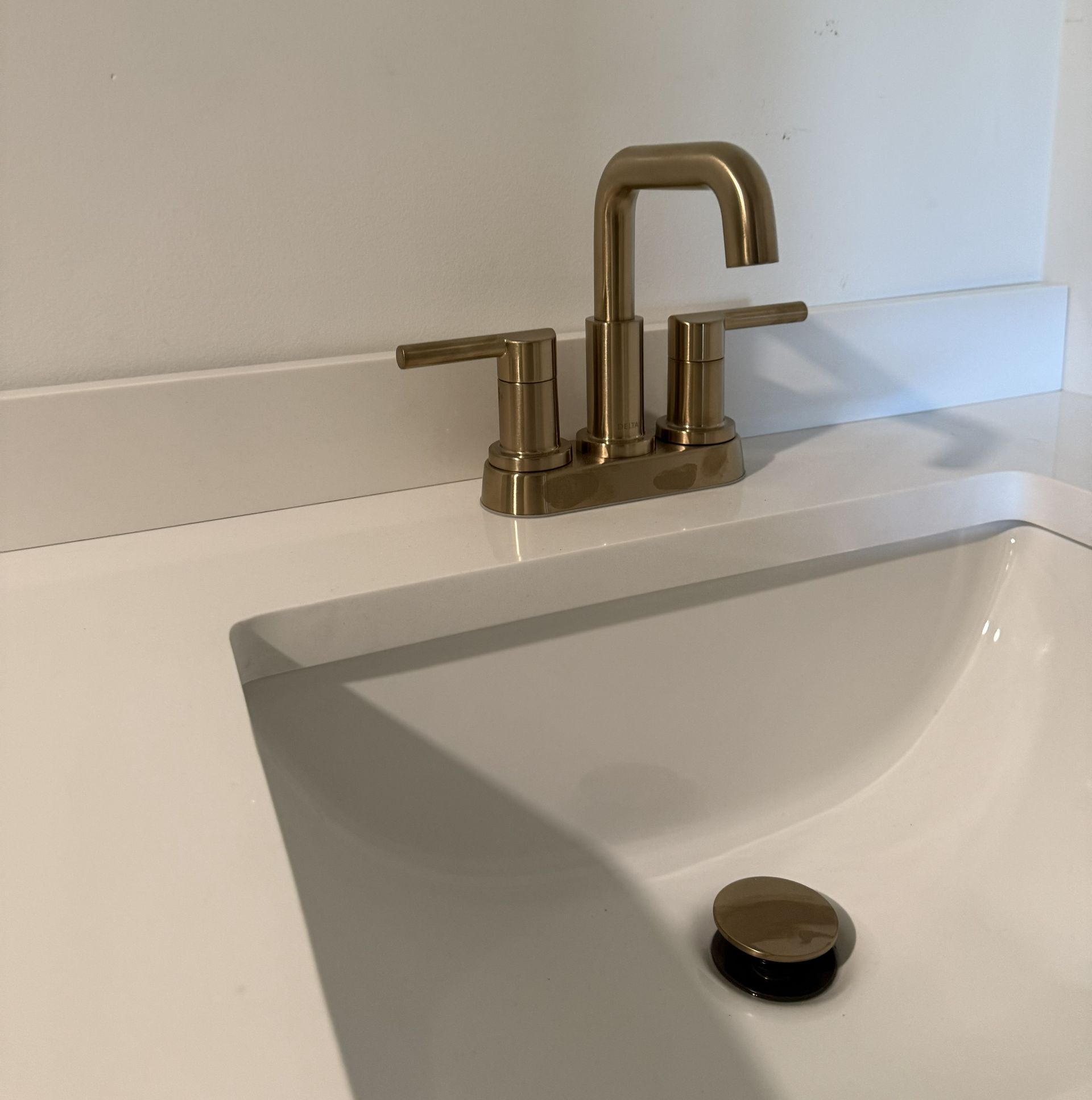 Modern bathroom with a light wood vanity, vessel sink, gold faucet, and wall-mounted mirror.