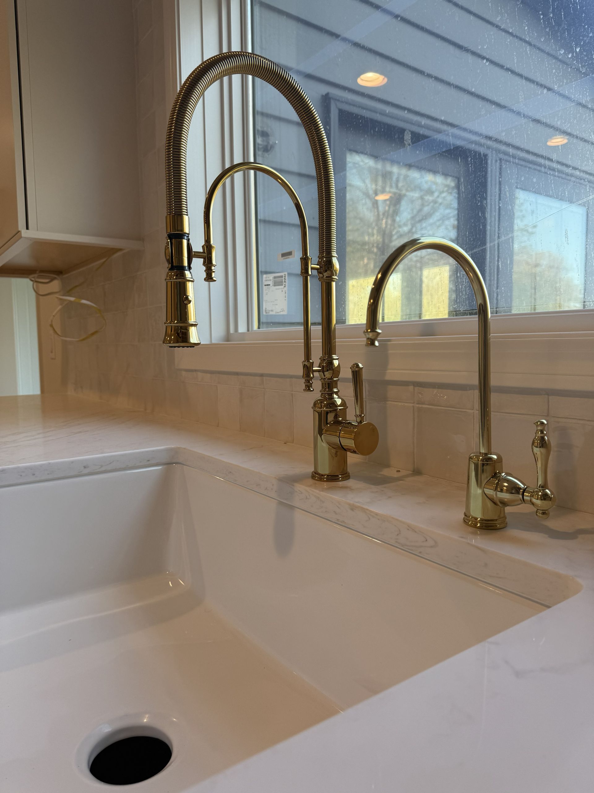 Stainless steel kitchen sink with faucet, granite countertop, and window overlooking a green yard.