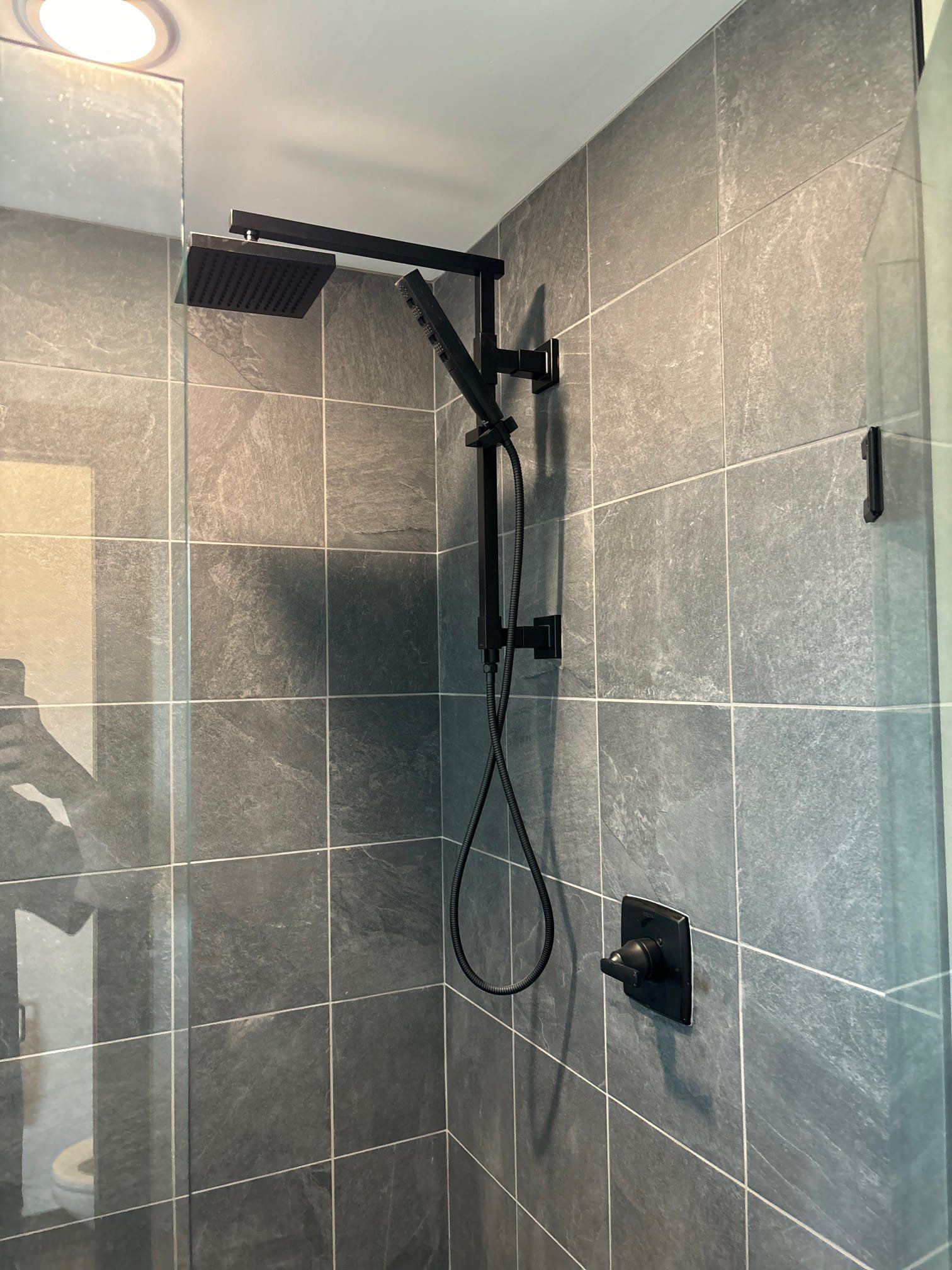 Gold shower fixtures against dark gray tiled walls.