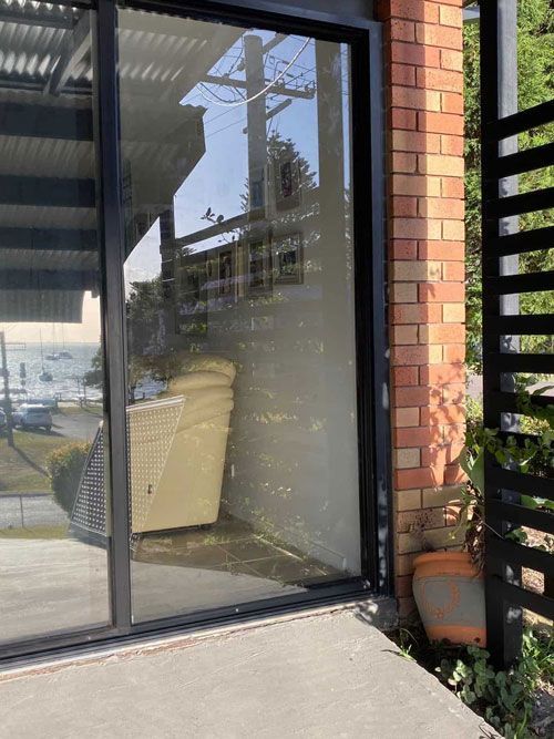 A Sliding Glass Door with A Reflection of A Patio in It — Reflect Glass In Tuggerah, NSW