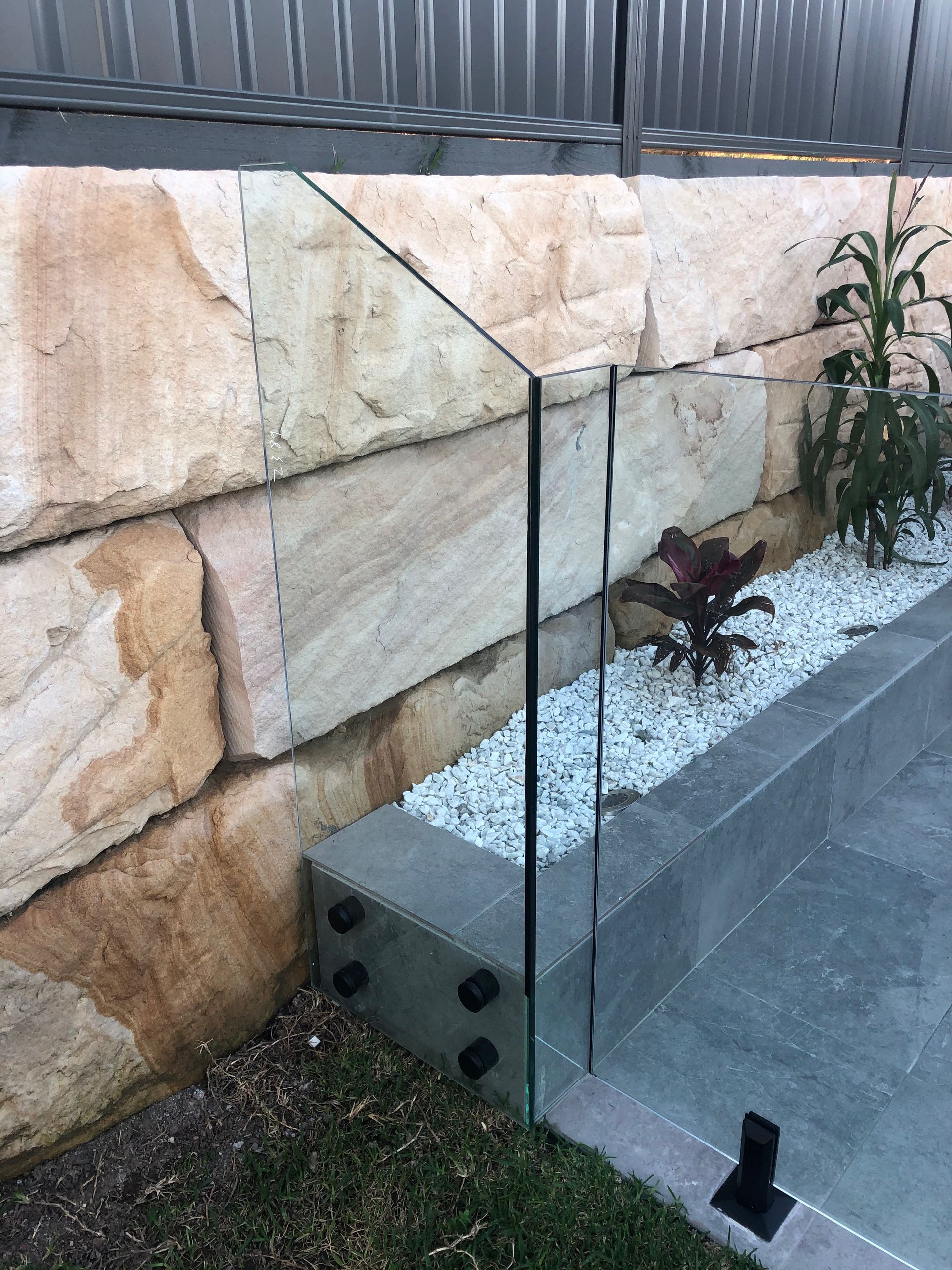 A Stone Wall with A Glass Railing in Front of It — Reflect Glass In Tuggerah, NSW