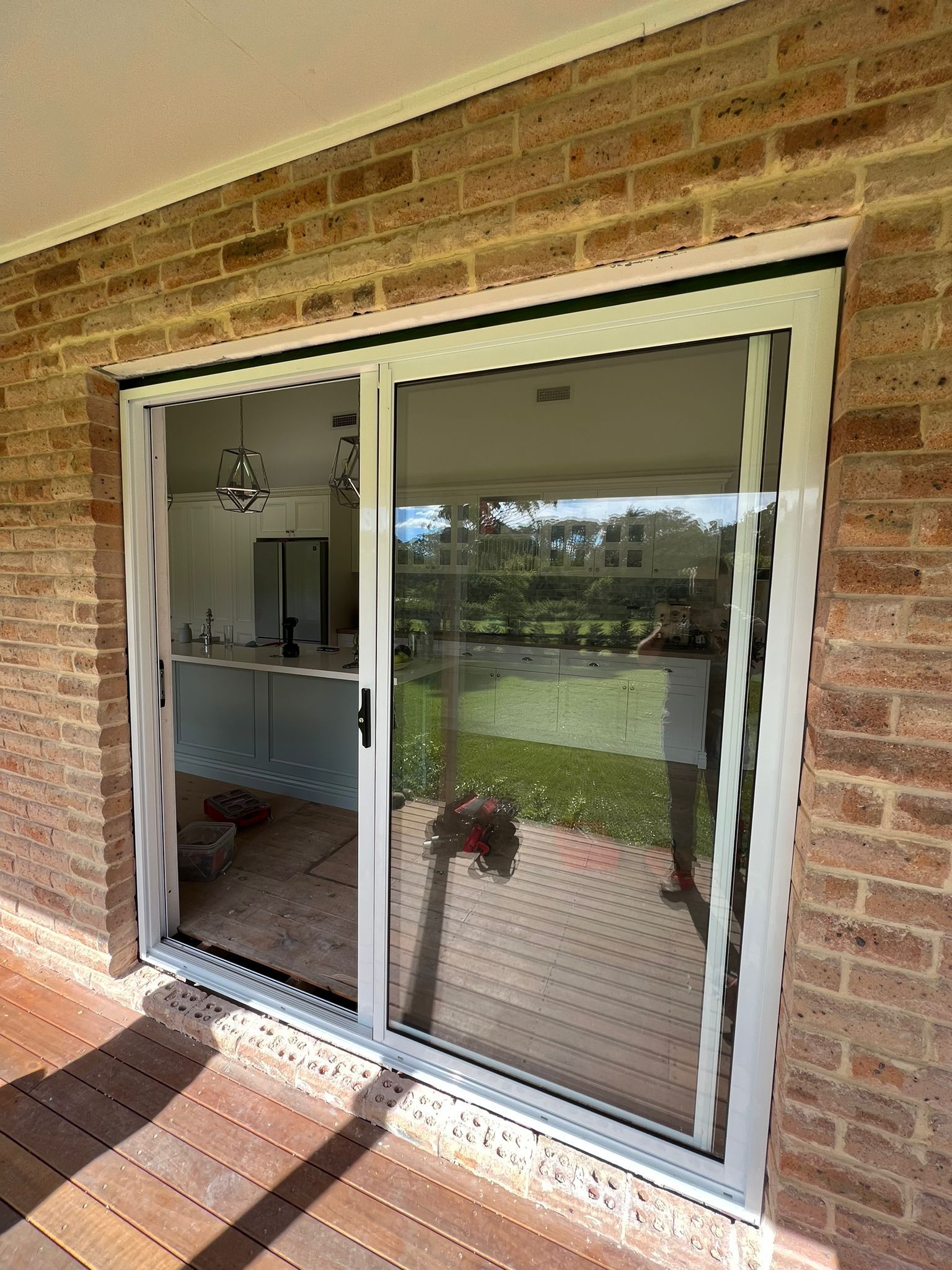 A Sliding Glass Door Is Sitting on Top of A Wooden Deck — Reflect Glass In Tuggerah, NSW